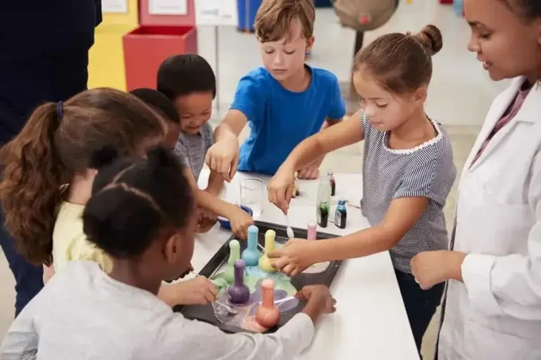 Children and an instructor conducting science experiments with colorful test tubes and beakers in a classroom setting